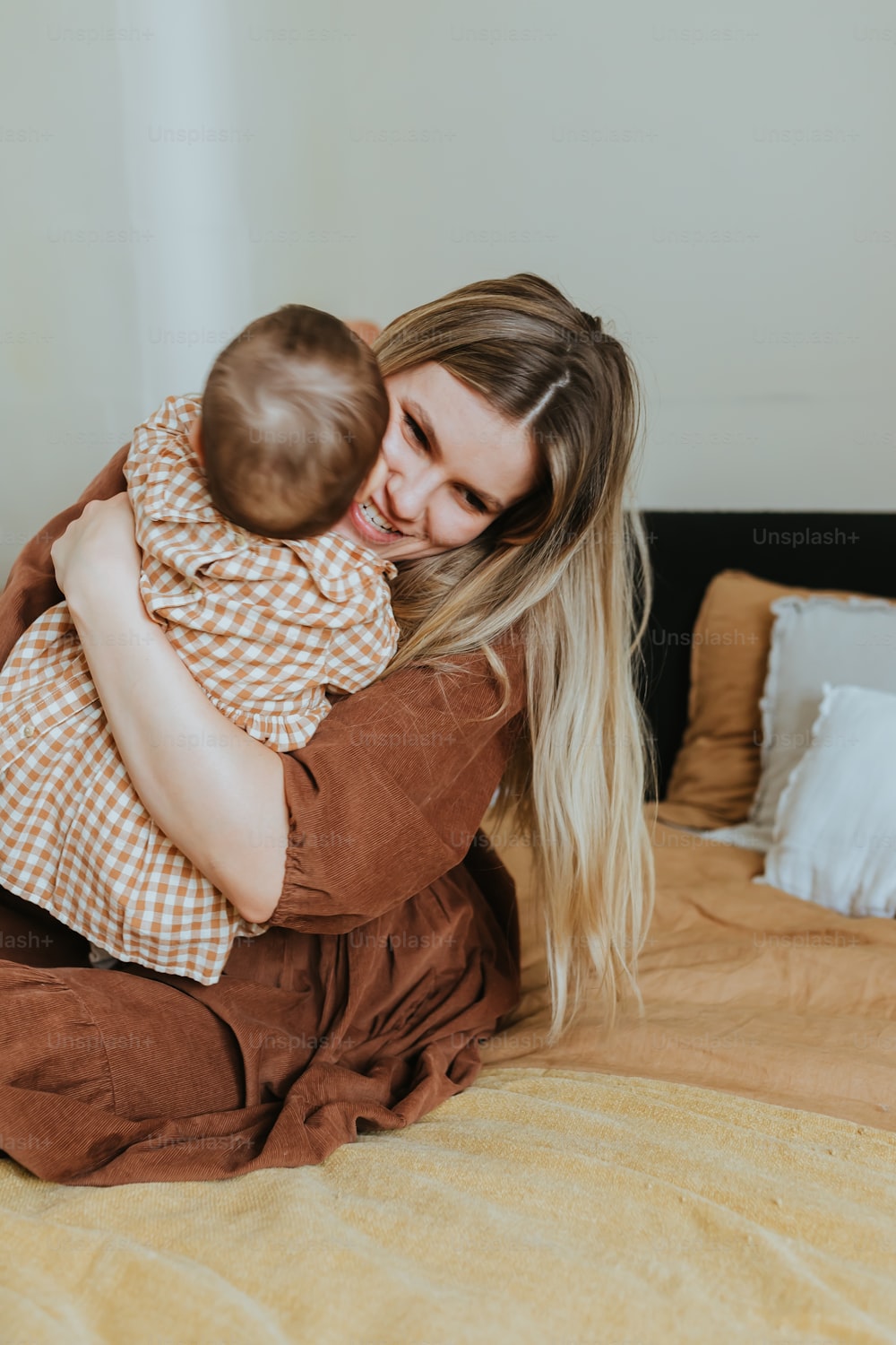 a woman holding a baby on top of a bed