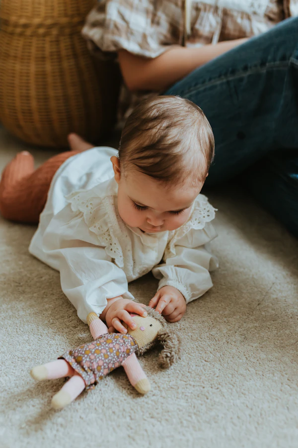 Bébé jouant joyeusement avec un doudou par terre