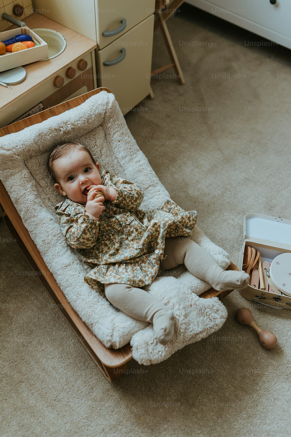 a baby in a rocking chair with a book on the floor
