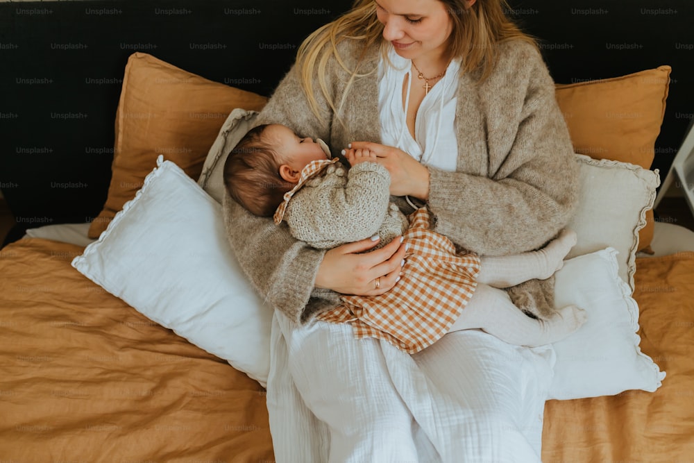 a woman sitting on a bed holding a baby
