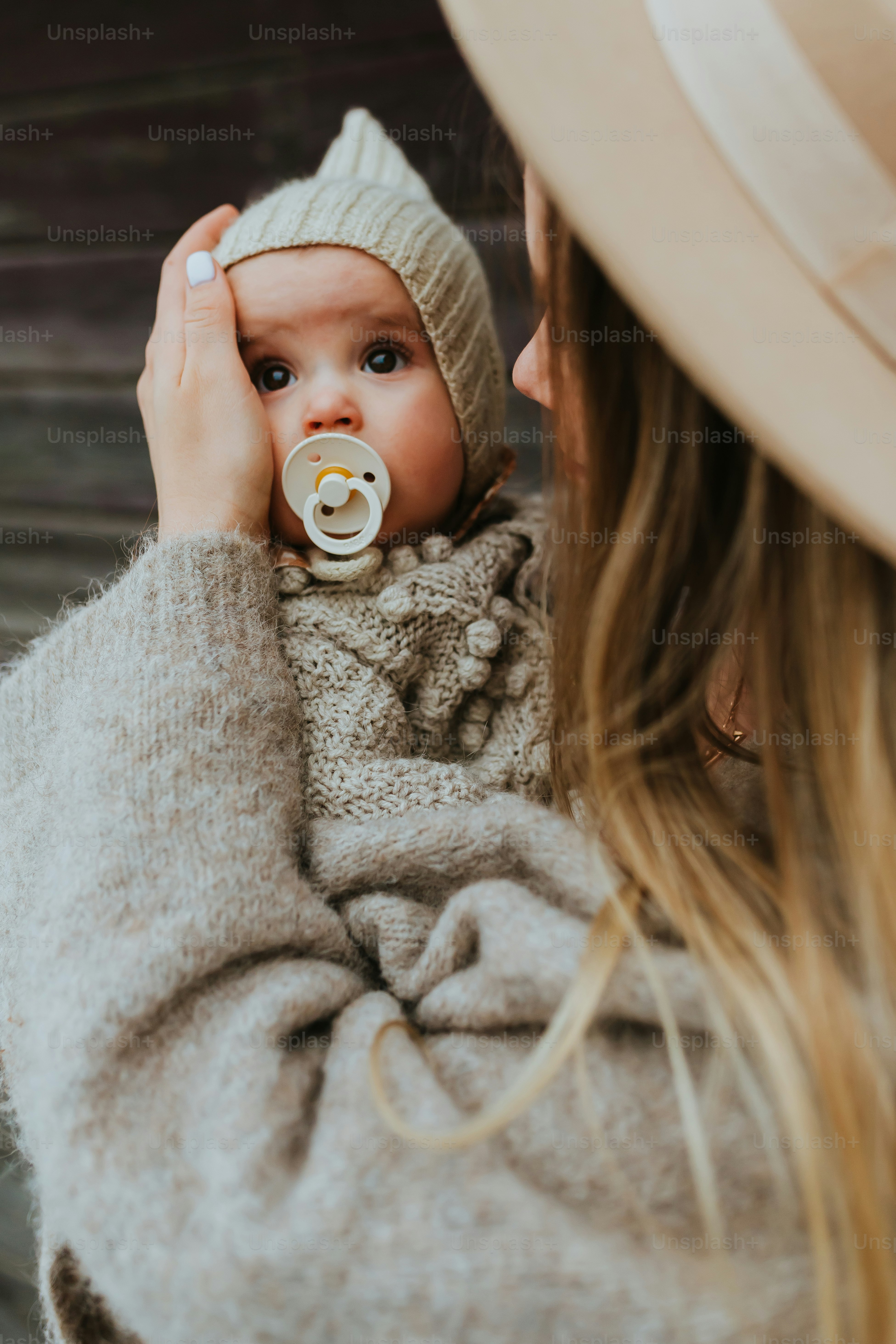 a woman holding a baby wearing a hat