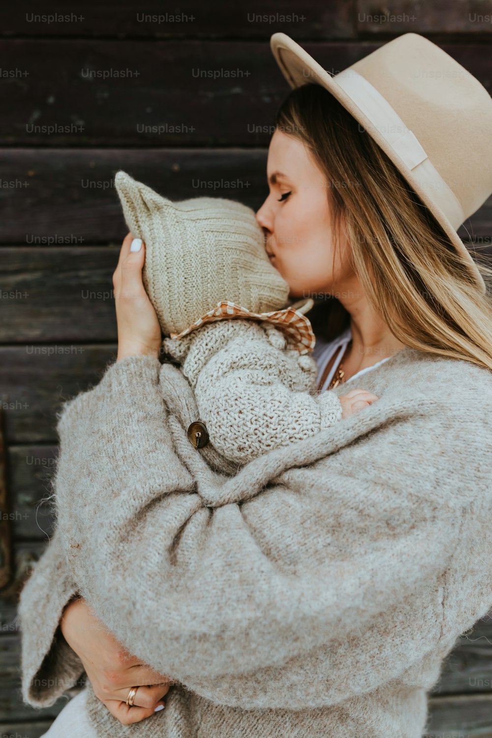 a woman in a hat and sweater holding a pillow