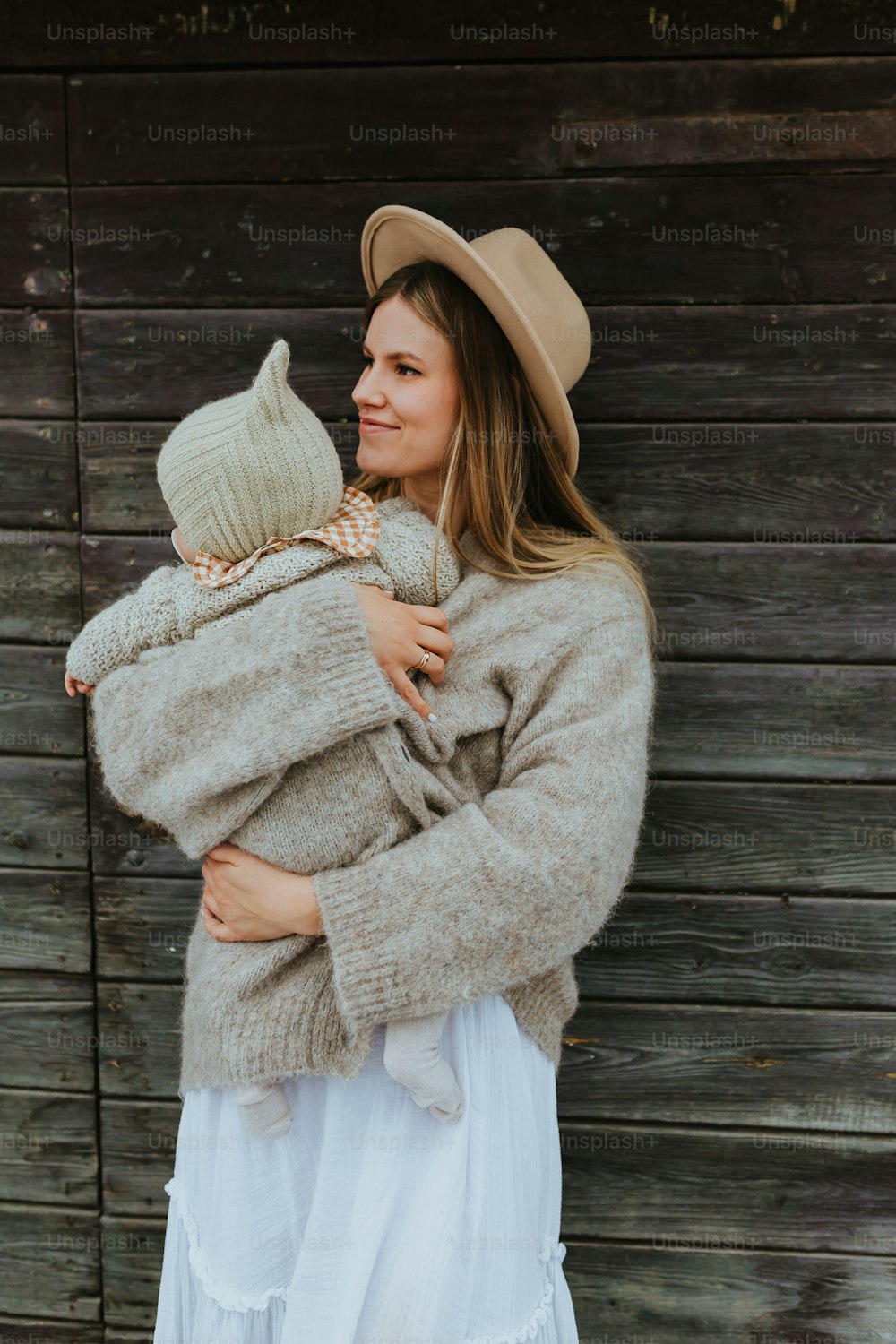 赤ん坊を腕に抱く帽子をかぶった女性