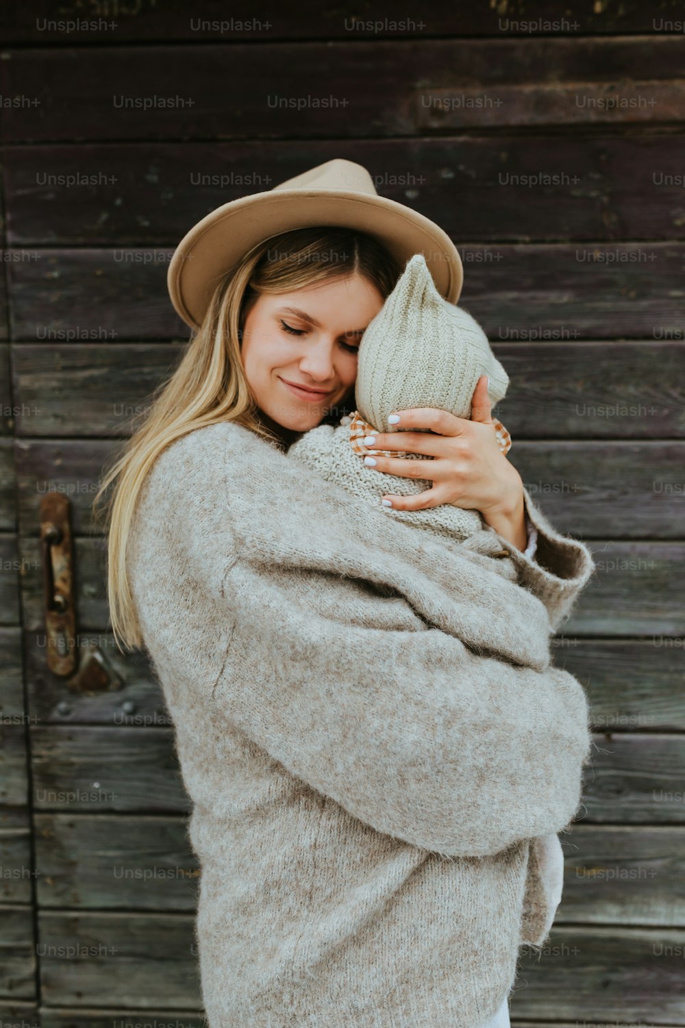Una mujer con un sombrero y un suéter abrazándola