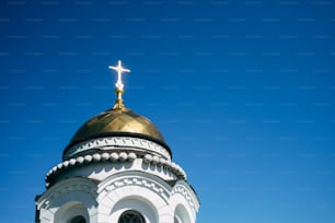Una iglesia blanca y dorada con una cruz en la parte superior