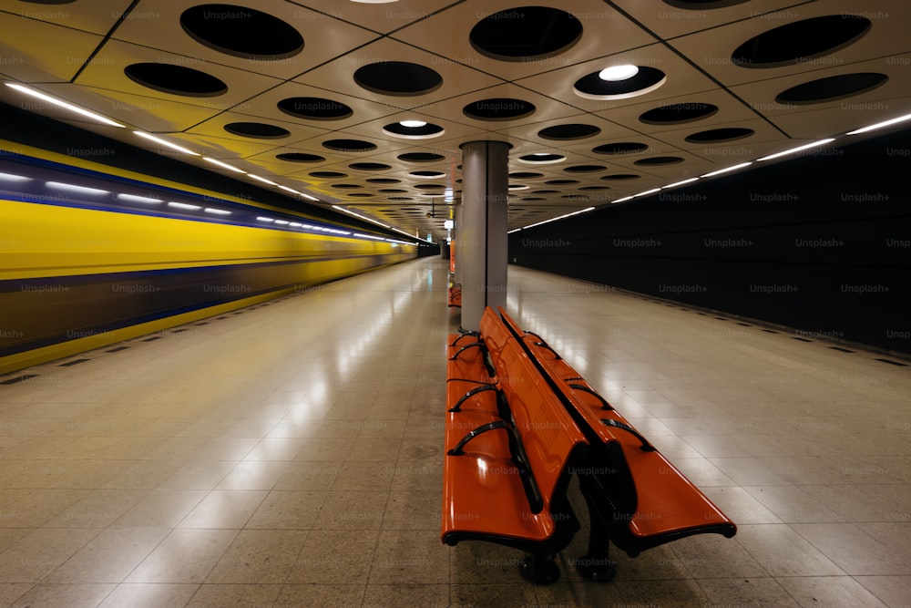 eine lange orangefarbene Bank in der Mitte eines Tunnels