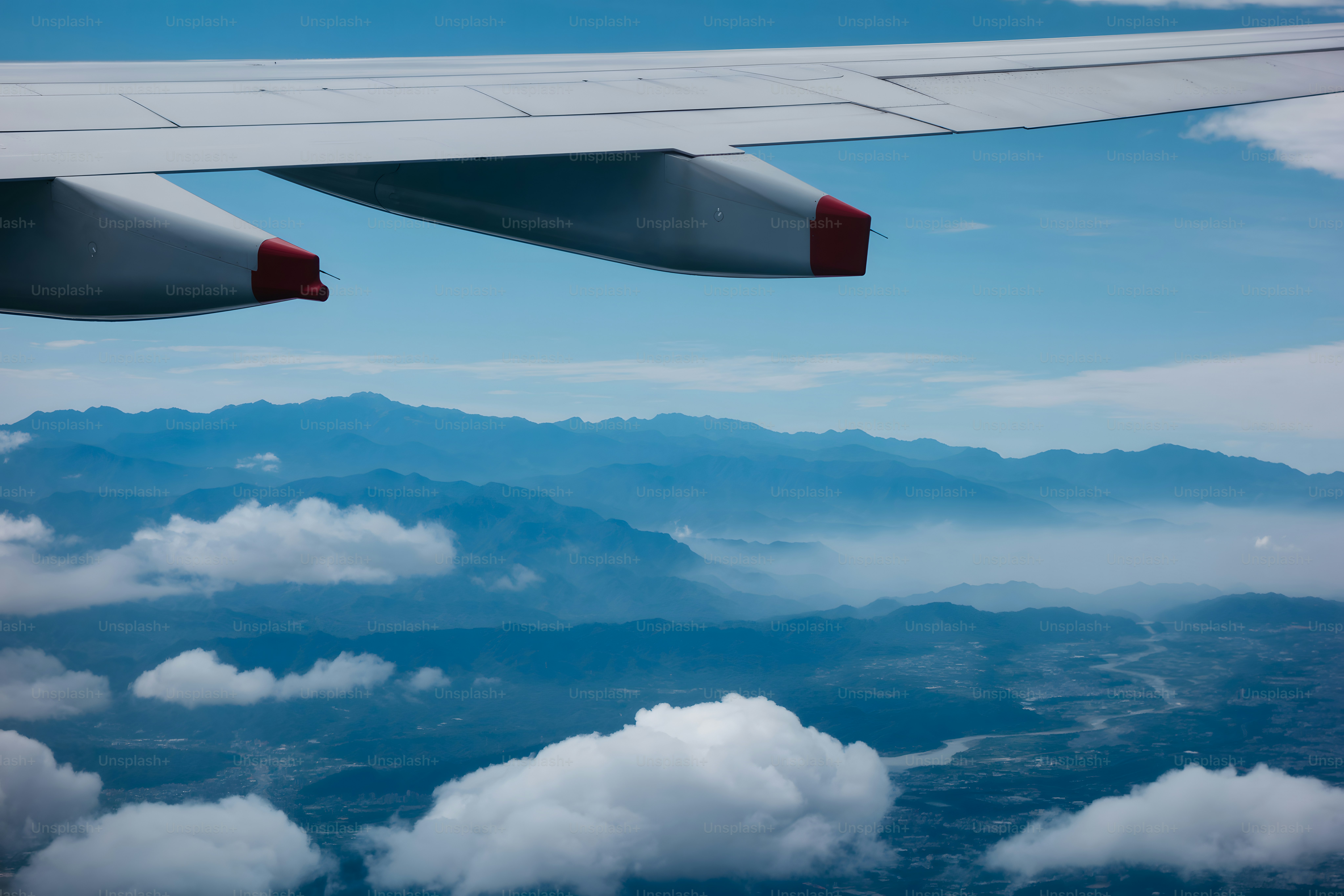 Der Flügel eines Flugzeugs, das über eine Bergkette fliegt