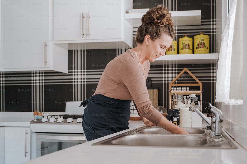 a woman is washing dishes in a kitchen