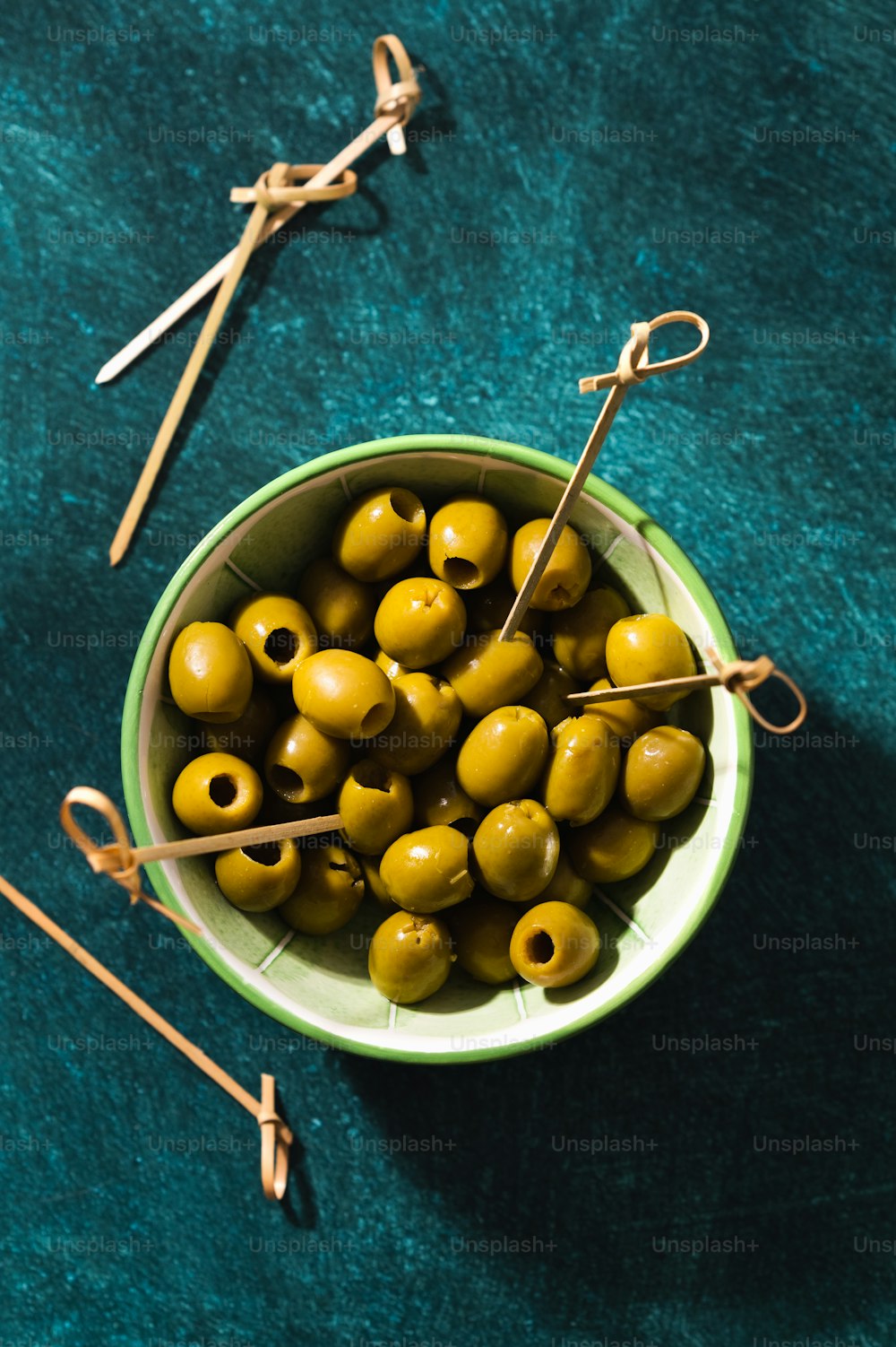 a bowl of green olives with a pair of knitting needles