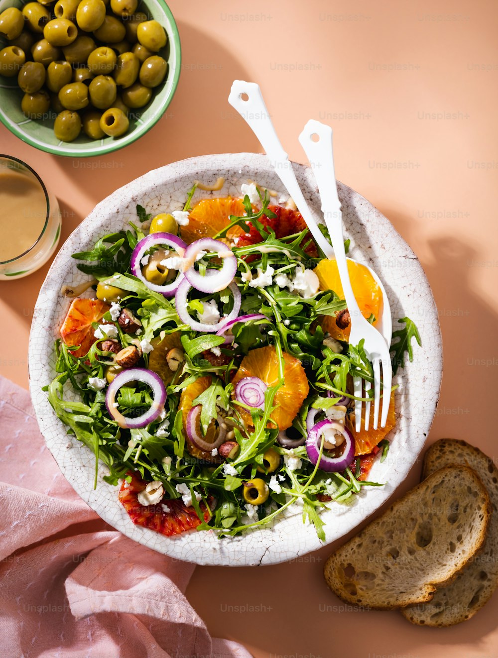 una ciotola bianca piena di insalata accanto a una ciotola di olive