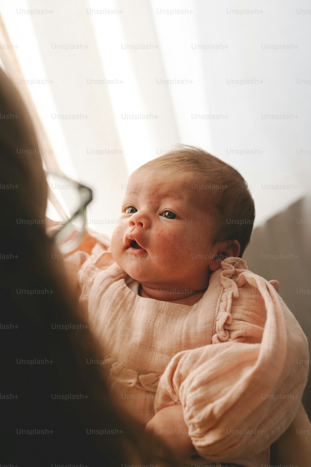 um bebê em um vestido rosa olhando para cima para algo