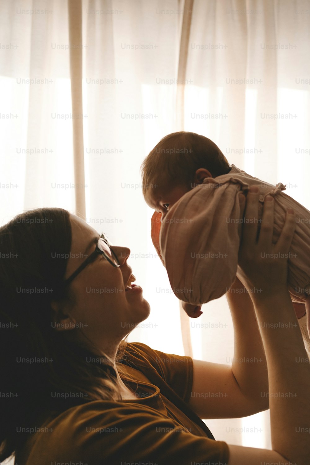 赤ん坊を顔に抱く女性
