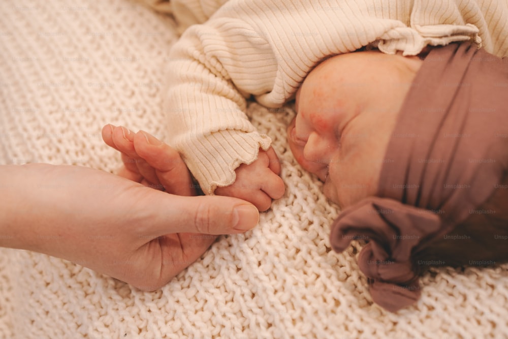 a person holding a baby's hand while laying on a bed