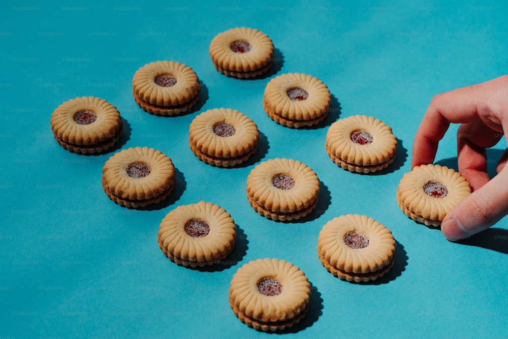 a hand reaching for a cookie on a blue surface