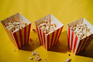 three red and white striped paper cups filled with popcorn