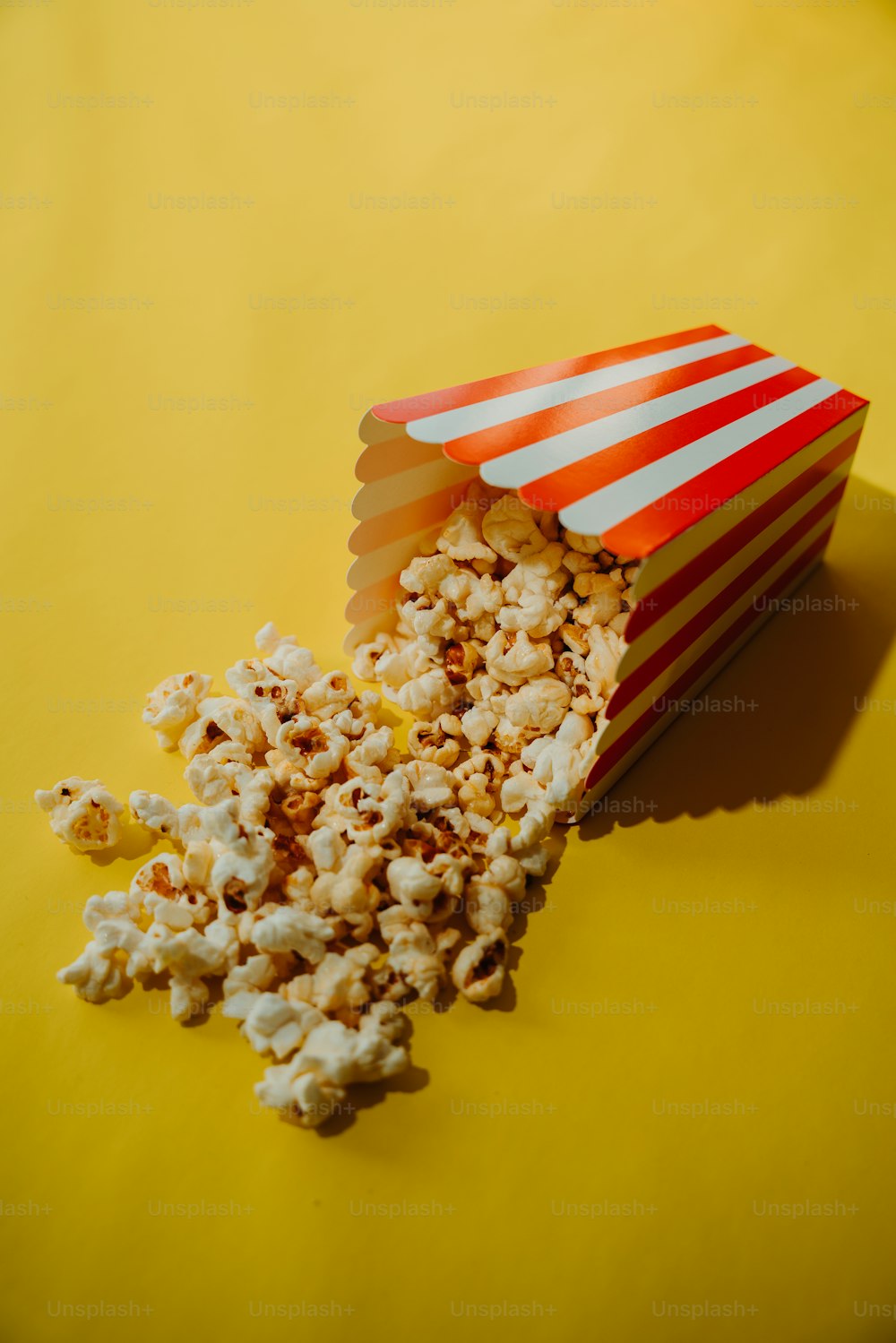 Eine Schachtel Popcorn auf einer gelben Oberfläche verschüttet