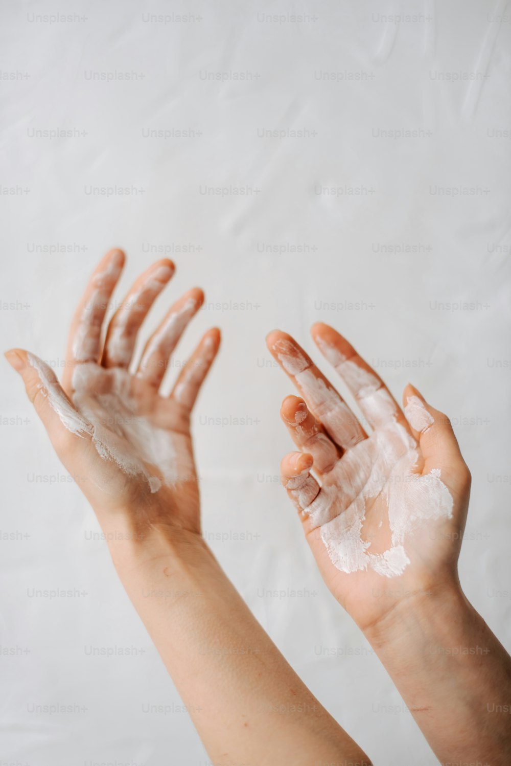 Zwei Hände sind mit weißem Pulver auf weißem Hintergrund bedeckt