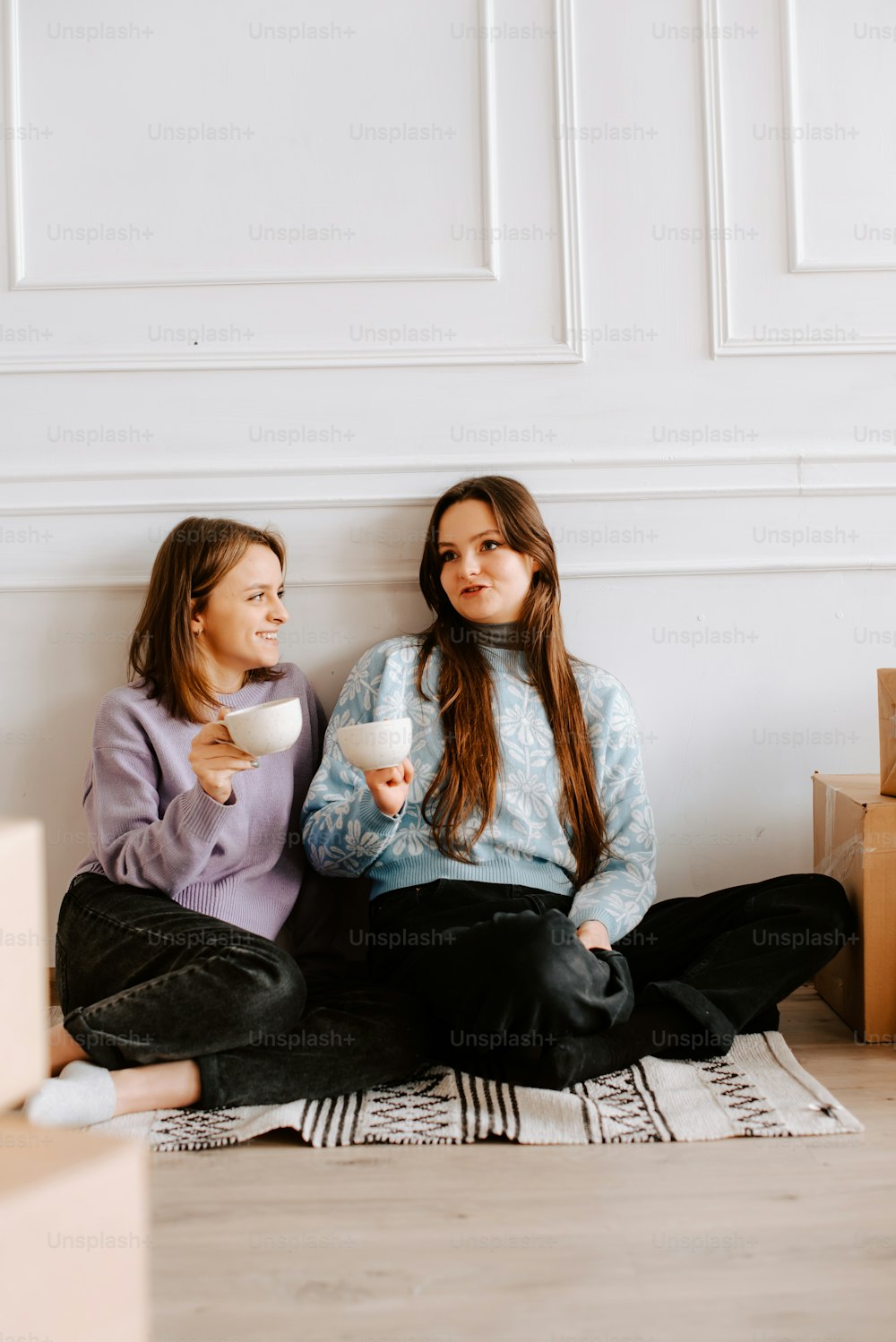 two young women sitting on the floor eating food