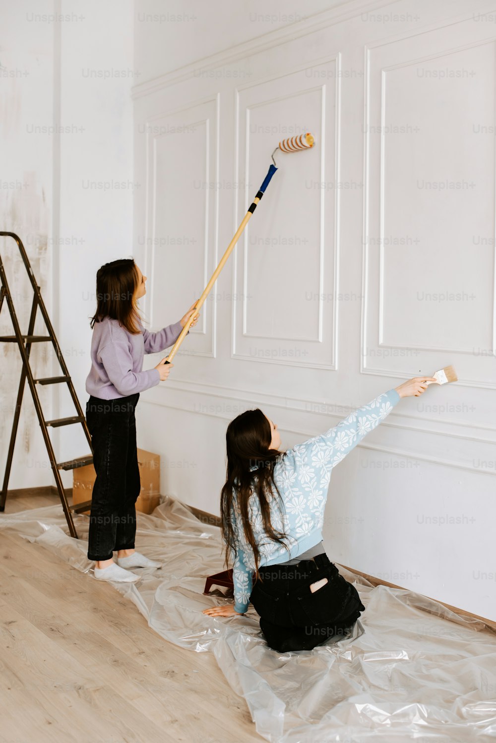 a woman and a girl are painting a wall