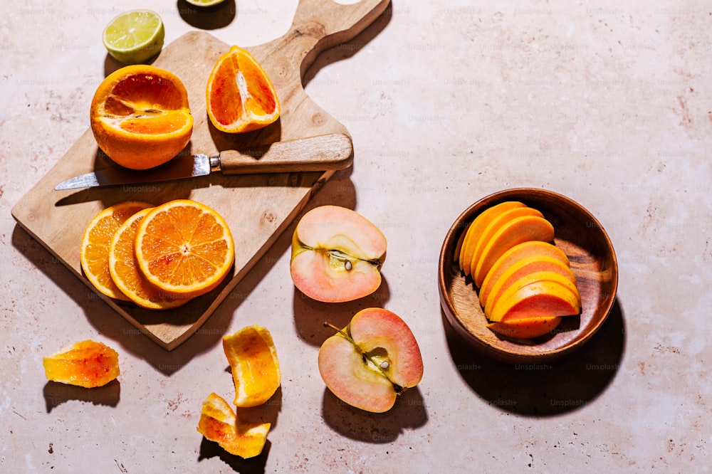una tabla de cortar cubierta con naranjas y manzanas en rodajas