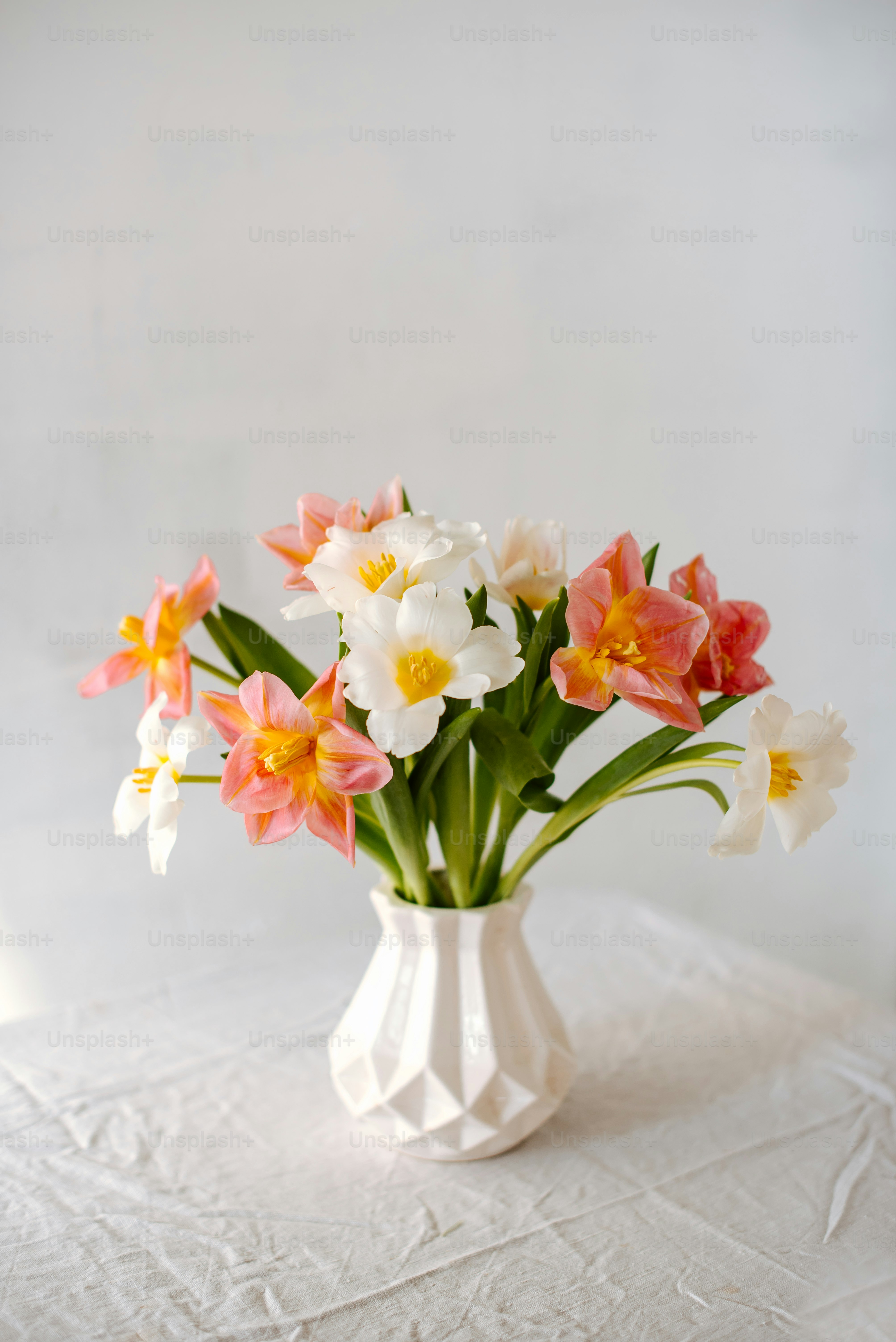 eine weiße Vase gefüllt mit bunten Blumen auf einem Tisch