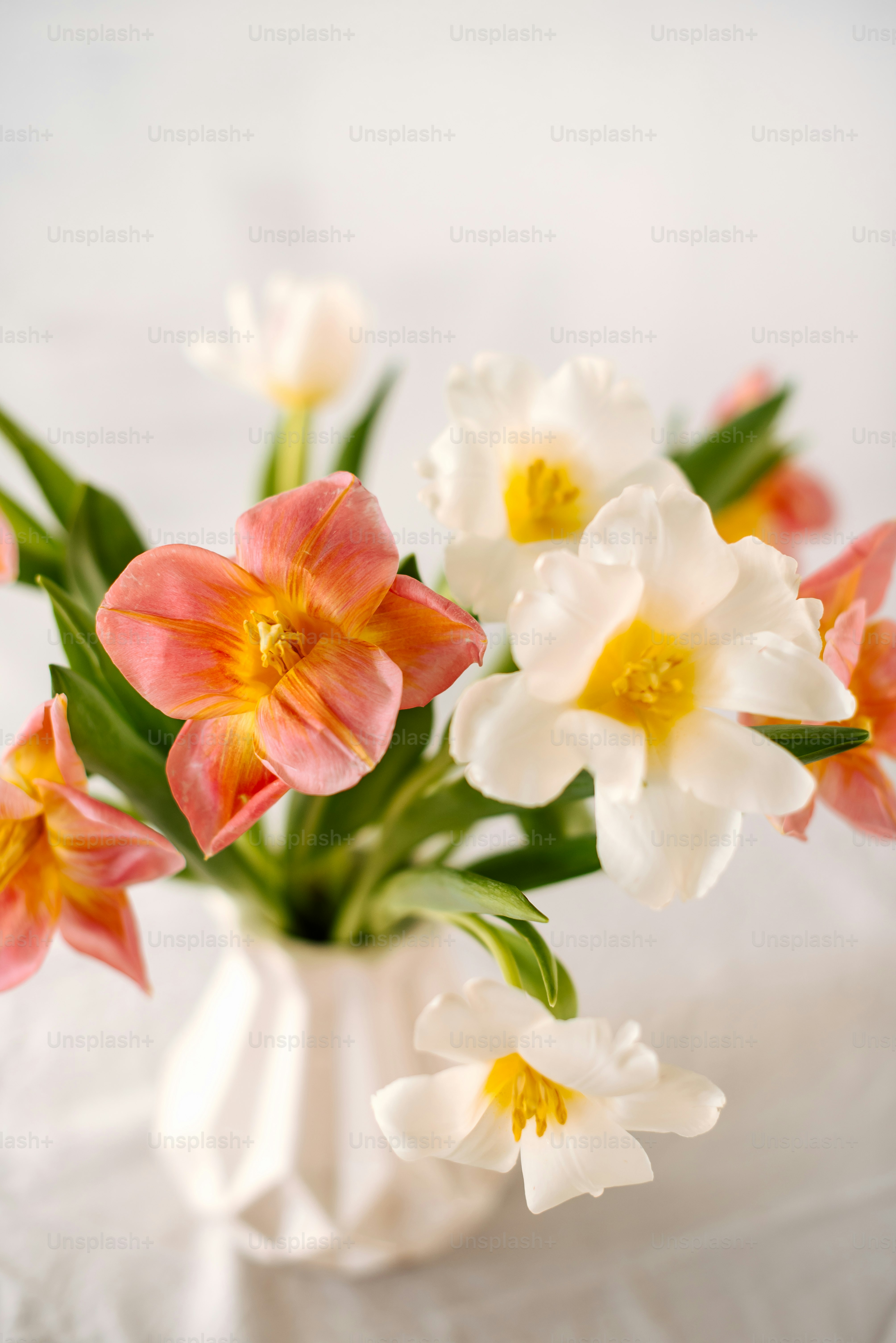 a white vase filled with pink and white flowers