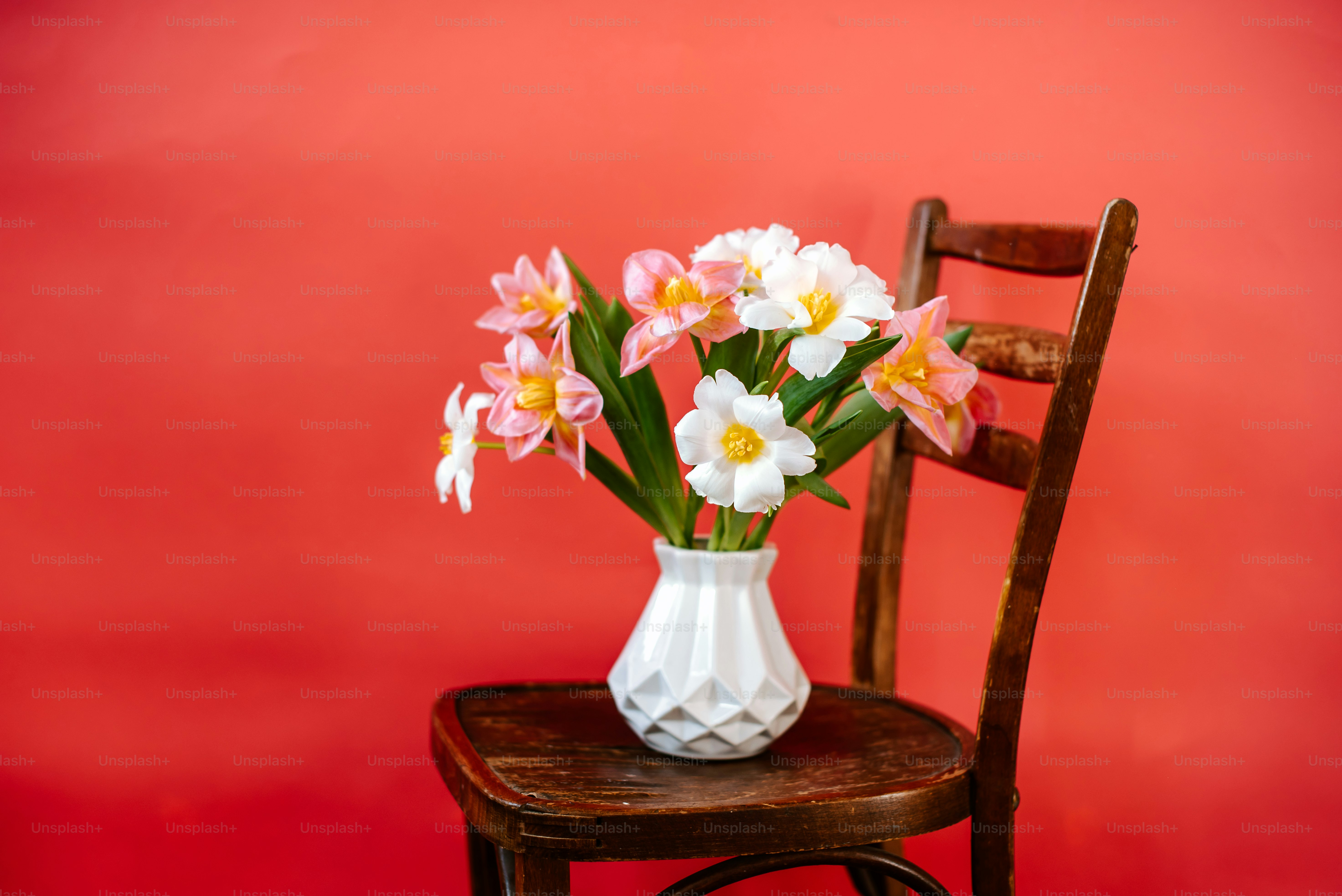 a white vase filled with pink and yellow flowers