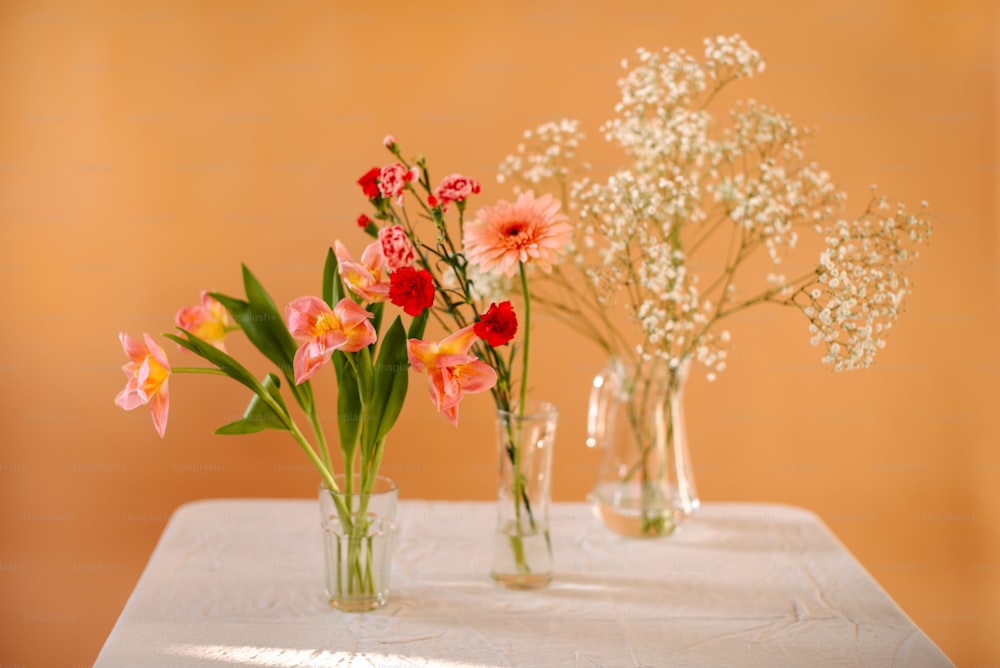 テーブルの上に座っている花でいっぱいの3つの花瓶