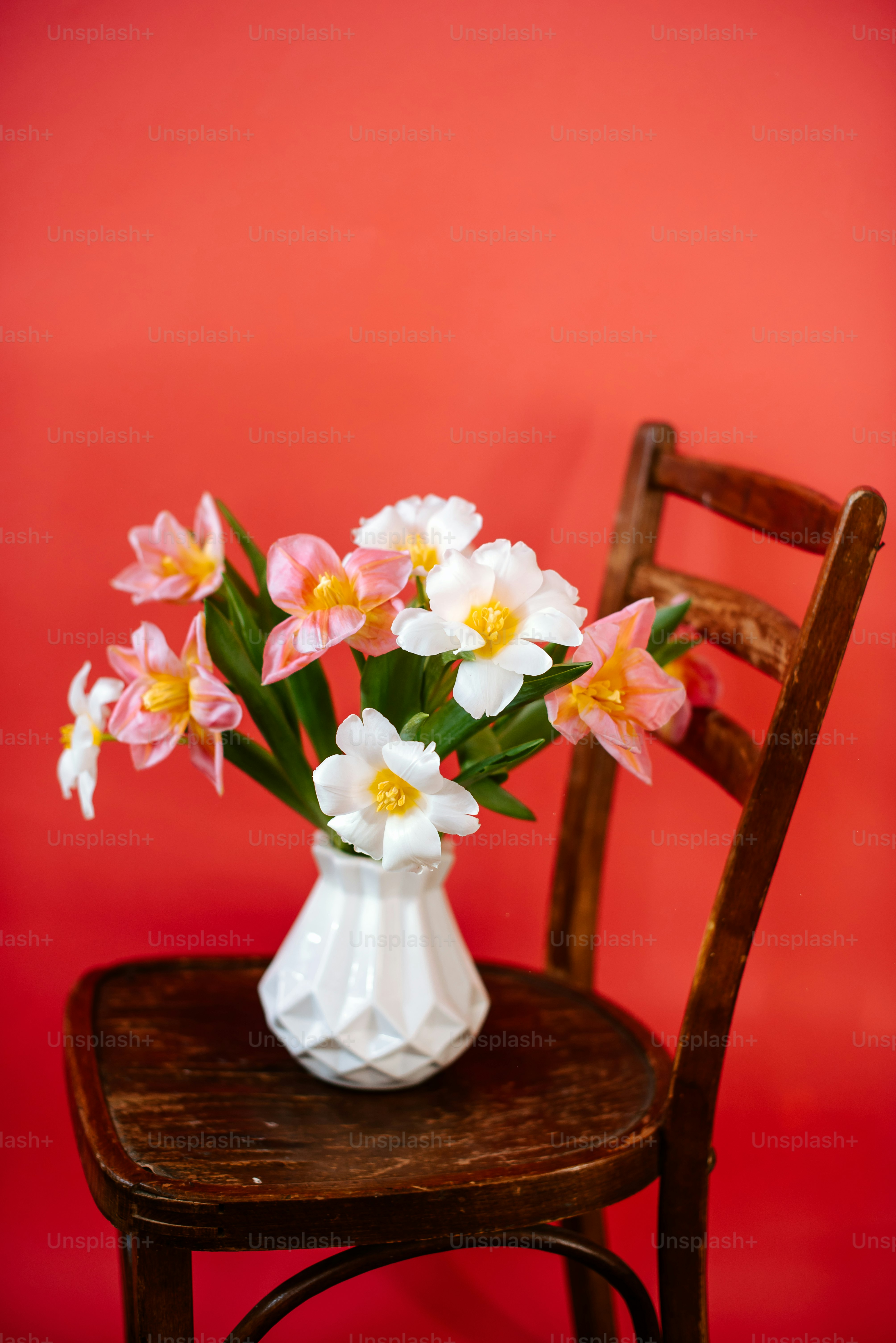 un vaso bianco pieno di fiori rosa e gialli