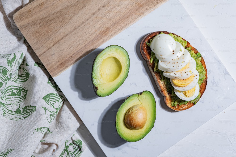 an avocado and poached egg sandwich on a cutting board