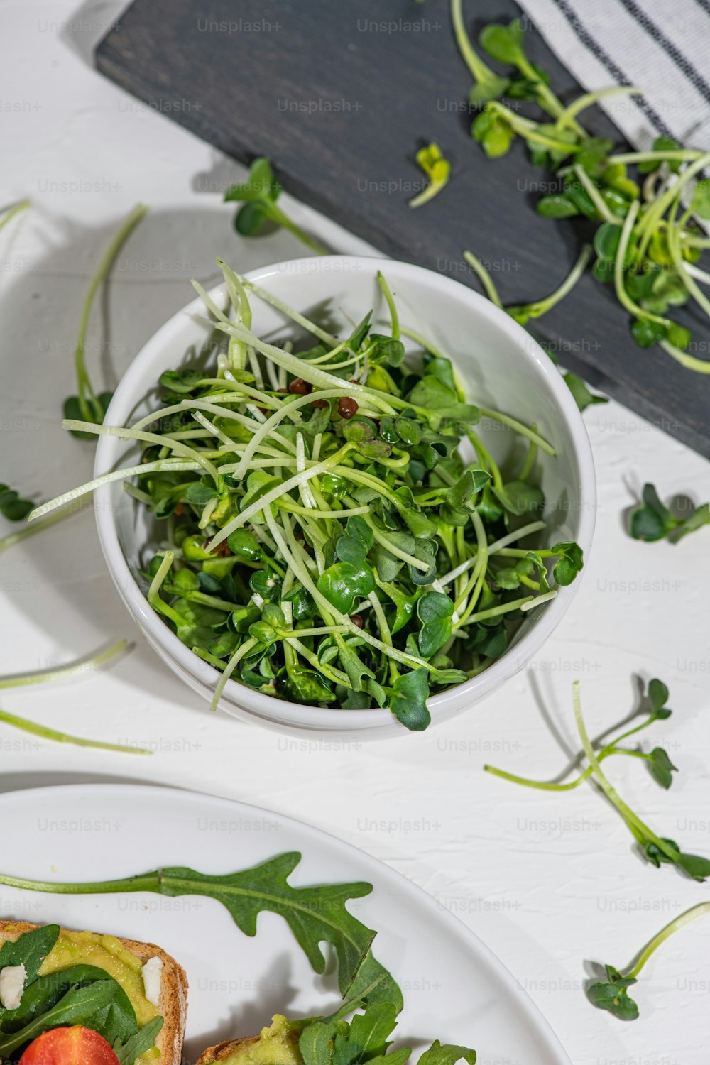 une assiette blanche garnie d’une salade à côté d’un bol de légumes verts