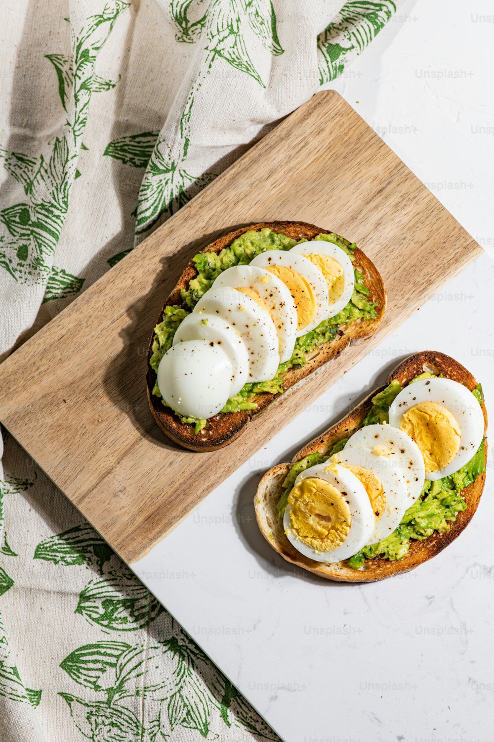 two halves of bread with eggs and avocado on a cutting board