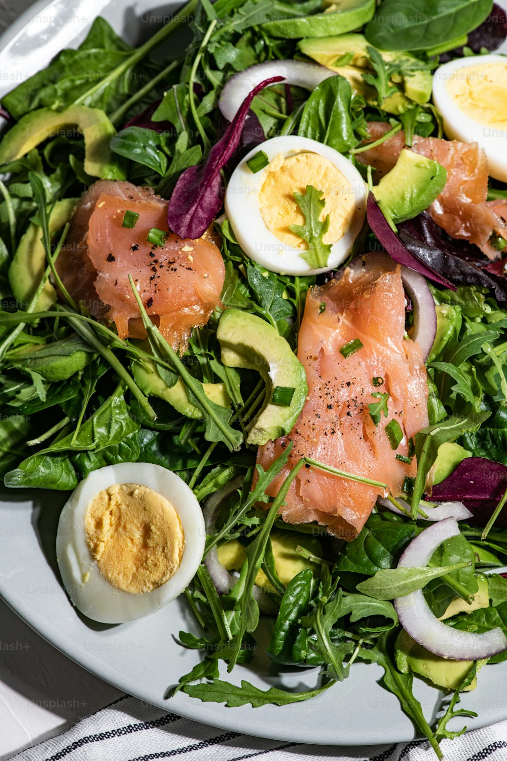 une assiette blanche garnie d’une salade et d’œufs durs