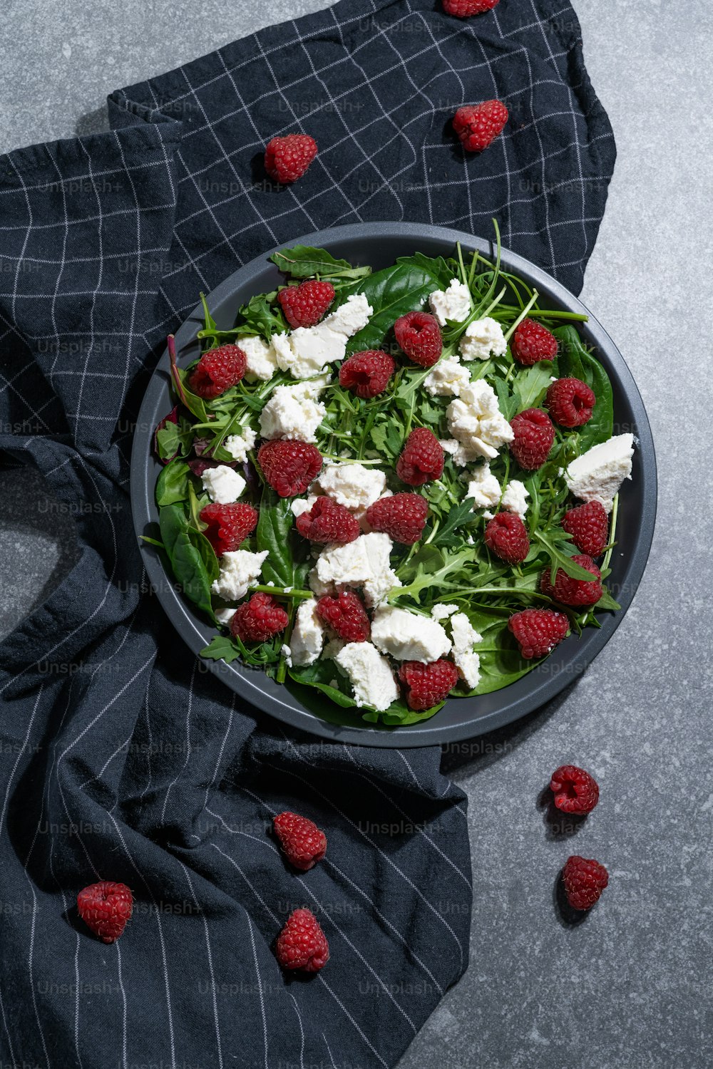 a bowl of salad with raspberries and feta cheese