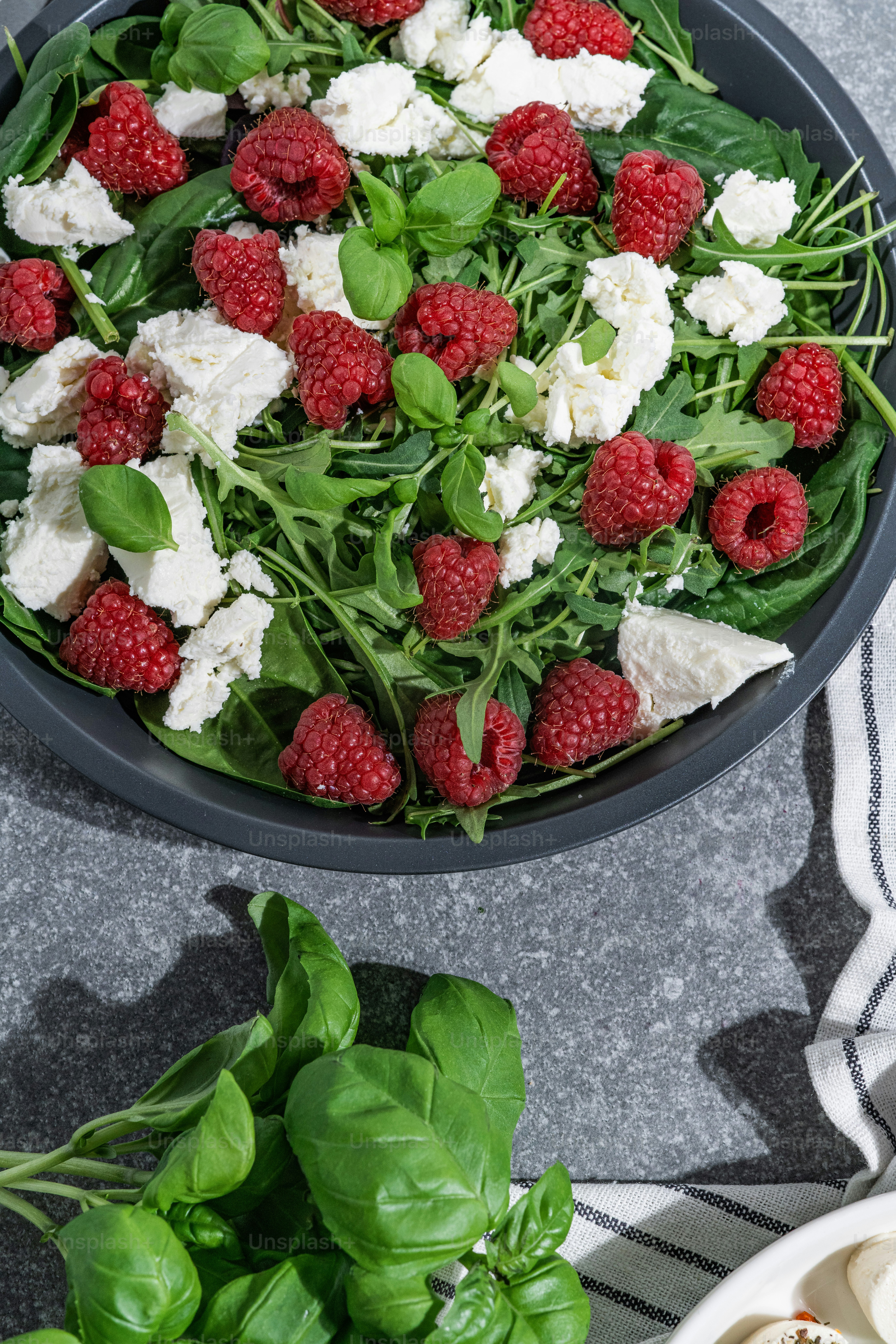 a bowl filled with spinach, cheese and raspberries