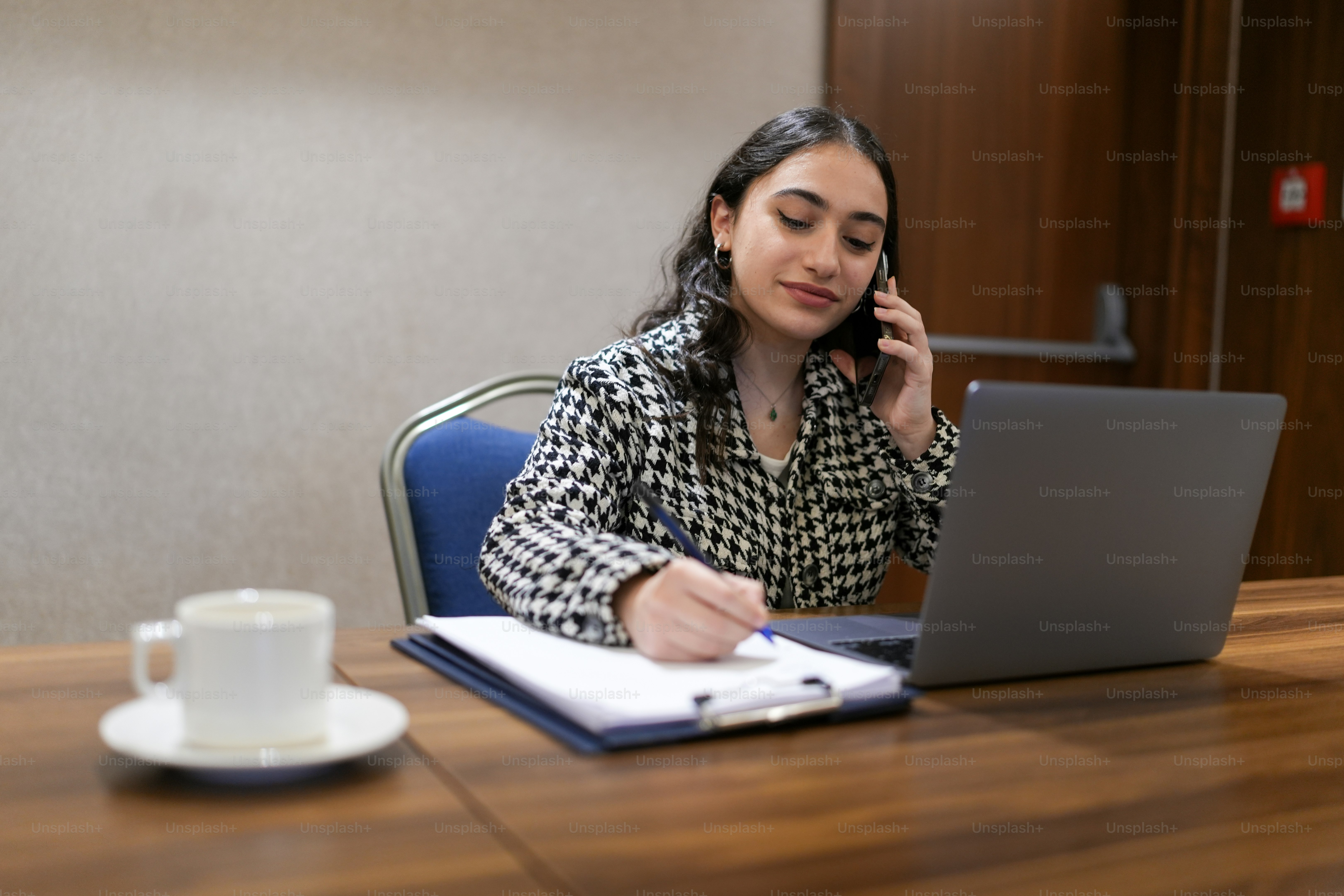 a woman sitting at a table talking on a cell phone