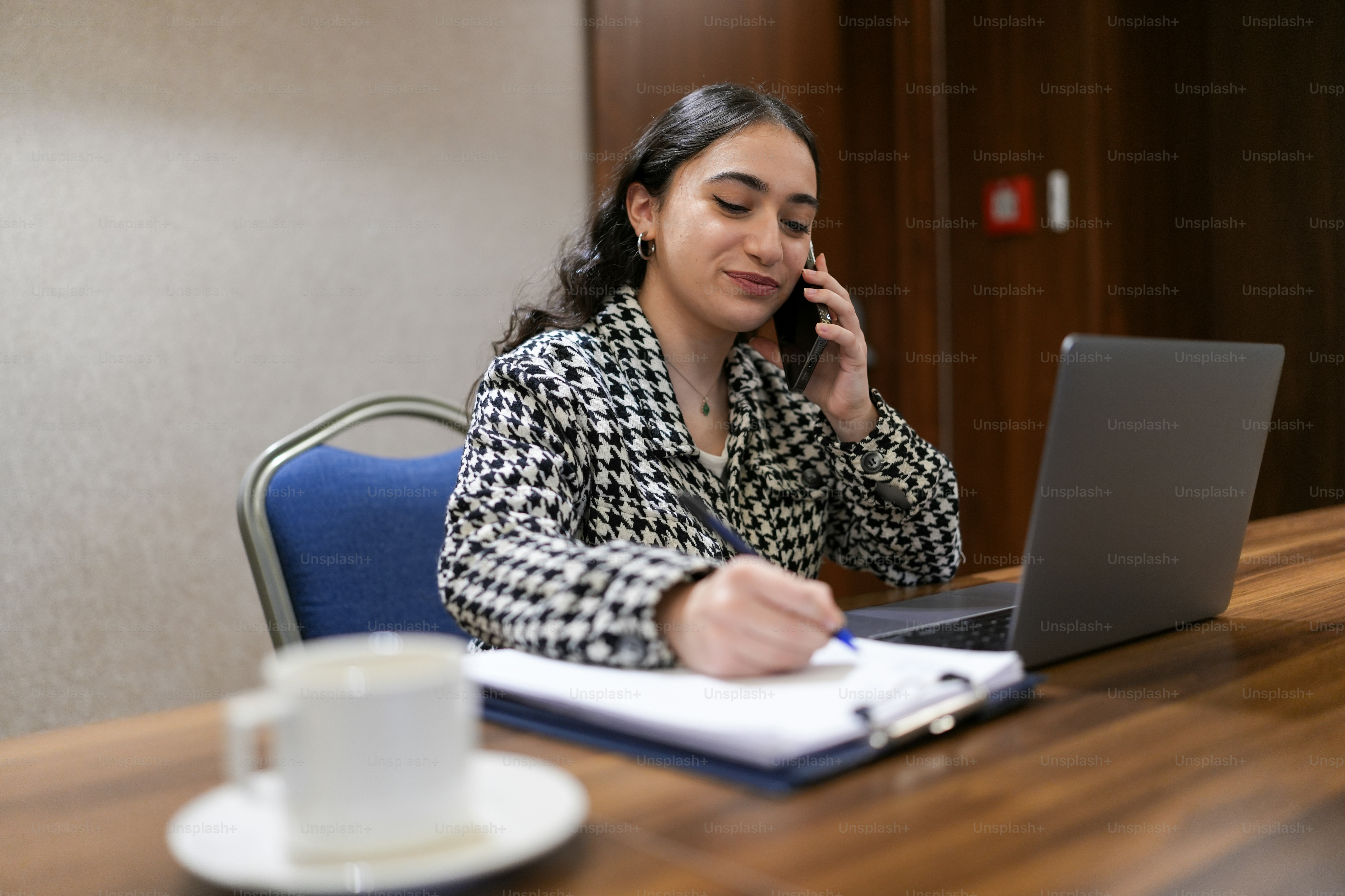 a woman sitting at a desk talking on a cell phone