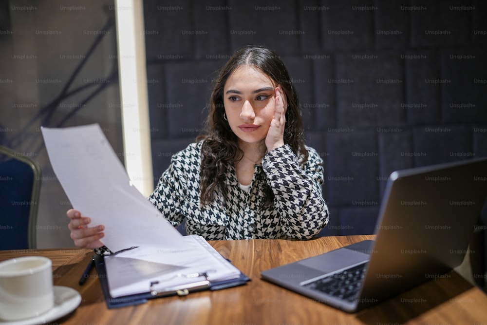 a woman sitting at a table with a laptop and papers in front of her