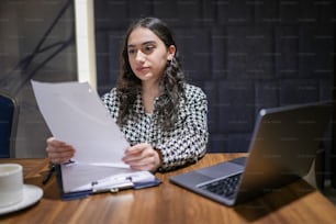 a woman sitting at a table with a laptop and papers