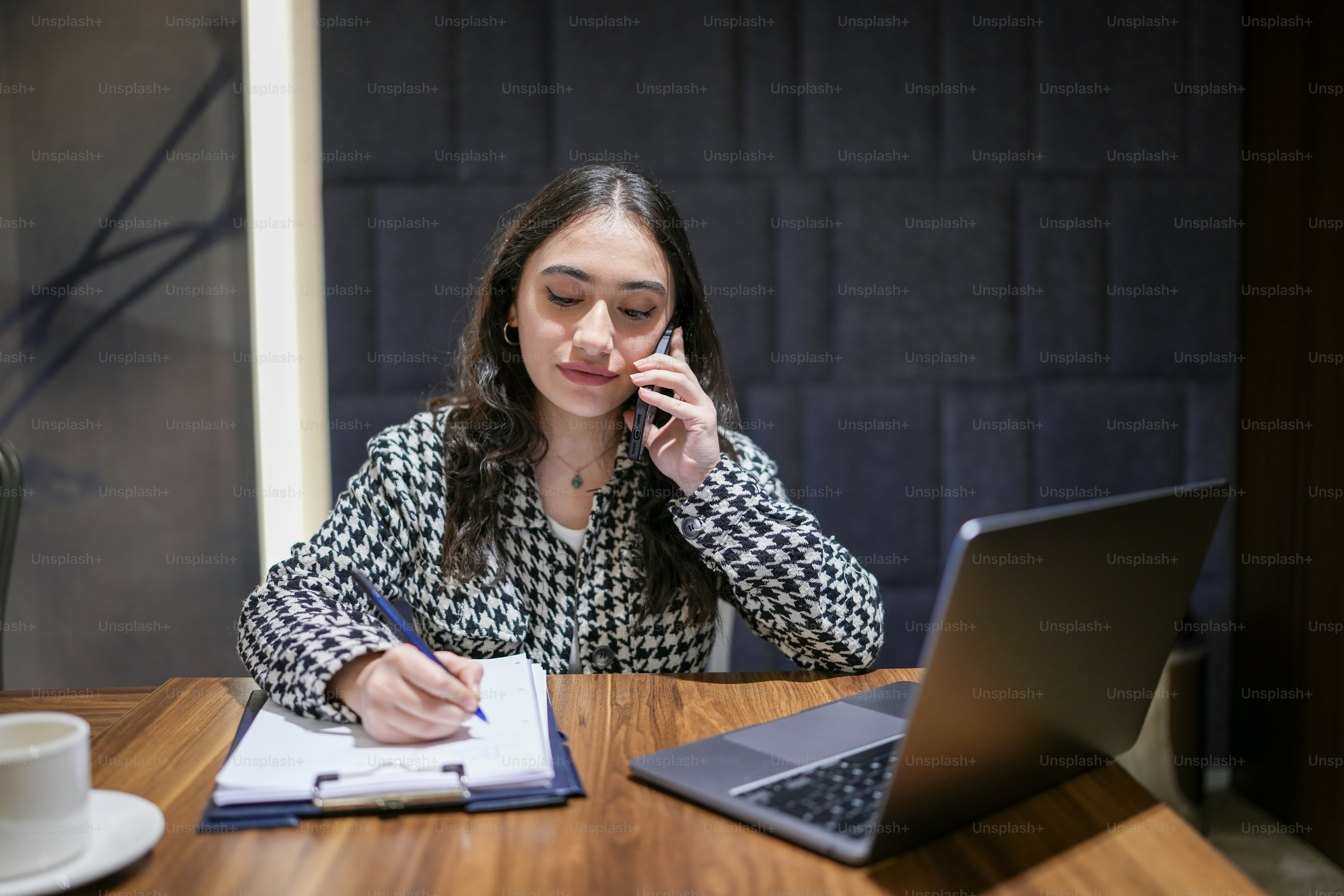 a woman sitting at a table with a laptop and a notebook