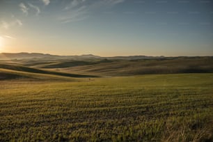 the sun is setting over the rolling hills