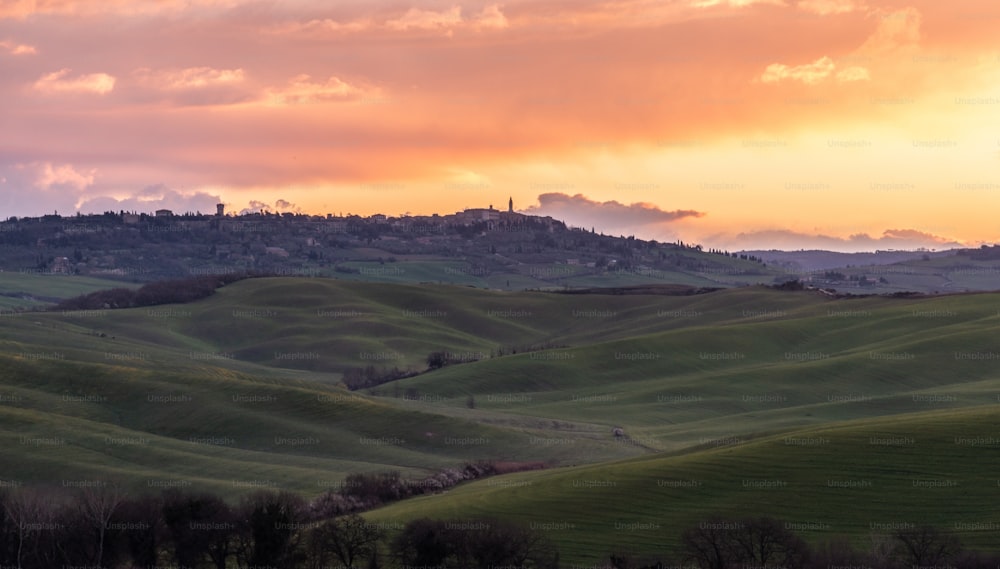 a sunset view of rolling hills with a city in the distance