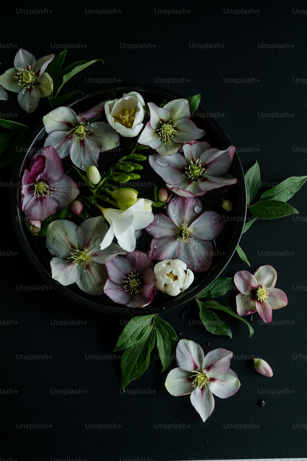 a black bowl filled with flowers on top of a table