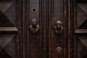 a close up of a wooden door with two statues on it