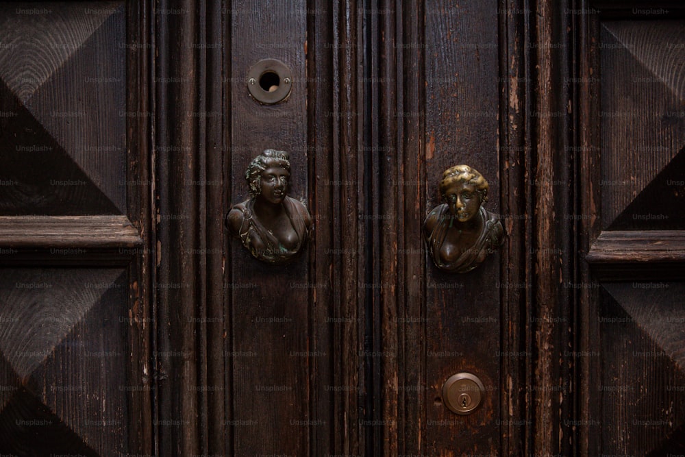 eine Nahaufnahme einer Holztür mit zwei Statuen darauf