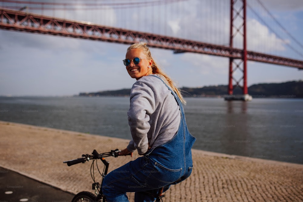 Eine Frau fährt Fahrrad neben einer großen Brücke