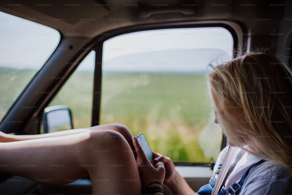 Eine Frau sitzt in einem Auto und schaut auf ihr Handy