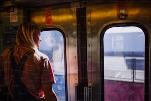 Una mujer parada en un tren mirando por la ventana