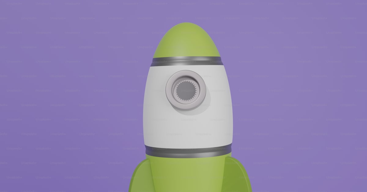 A green and white rocket ship sitting on top of a rock photo – Rockets ...