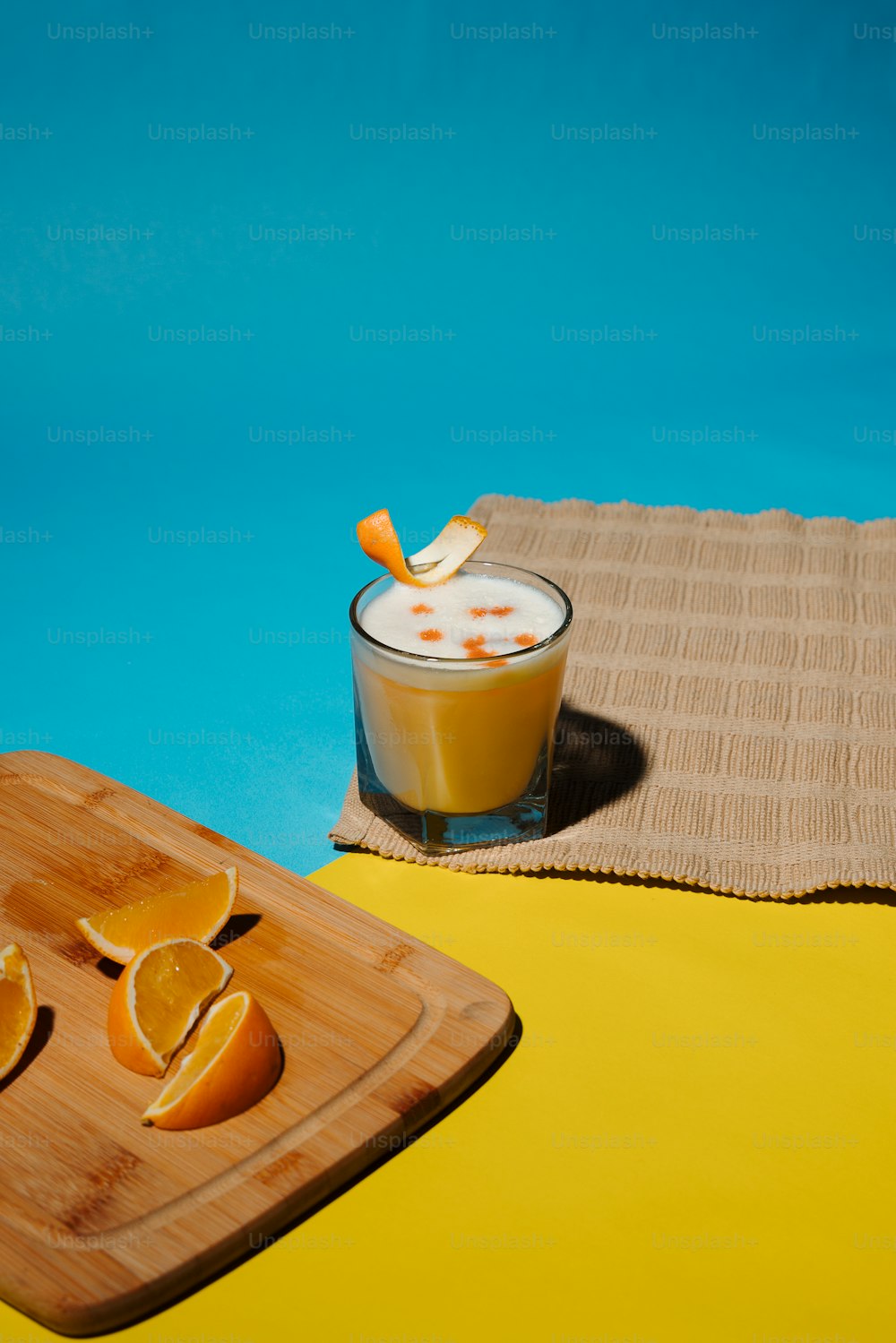 a glass of orange juice next to a cutting board